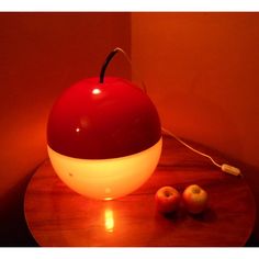 an apple sitting on top of a wooden table next to two apples and a light