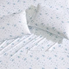 a bed with blue flowers on it and white sheets that have been rolled up to the side