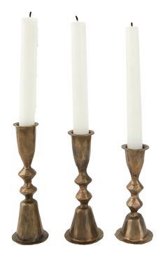 three brass candlesticks with white candles in them