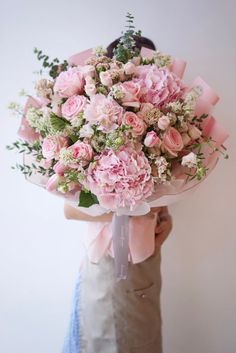 a woman holding a bouquet of pink flowers