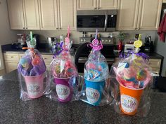 three plastic cups with toothbrushes in them sitting on a kitchen counter next to an oven