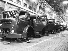 an old black and white photo of trucks on the assembly line in a factory building