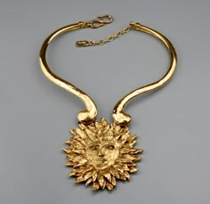 This Vintage Rare YVES SAINT LAURENT Sun Face Necklace is RARE and such a collector item. This was designed by Robert Goossens for YSL and was included in the Metropolitan Arts and Design Museum Exhibition on Fashion Jewelry -- The Collection of BARBARA BERGER. Very classic! A must have. Features: - 100% Authentic YVES SAINT LAURENT. - Adjustable chunky rigid necklace with sun face pendant. - The sun face pendant is intricately detailed, textured and raised. - Signed YSL Made in France. - S and Luxury Vintage Jewelry With Historical Design, Luxury Vintage Jewelry For Rodeo, Luxury Artistic Gold Necklaces, Luxury Retro Metal Jewelry, Luxury Gold Necklace For Fashion Statement, Luxury Vintage Jewelry With Artistic Design, Luxury Vintage Jewelry With Large Stone, Luxury Vintage Jewelry With Hallmarks, Luxury Statement Jewelry For Vintage Events