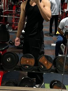 a man taking a selfie with his cell phone in front of some gym equipment