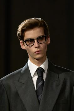 a young man wearing glasses and a suit