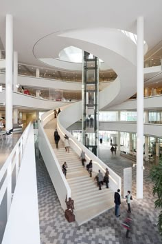 people are walking up and down an escalator in a large building with multiple floors