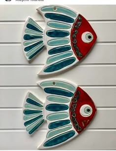 two red and blue fish are hanging on the wall next to each other with eyes