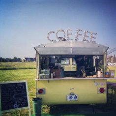 an old yellow truck parked in a field with a sign that says coffee on it