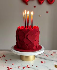 a red cake with hearts and candles on it