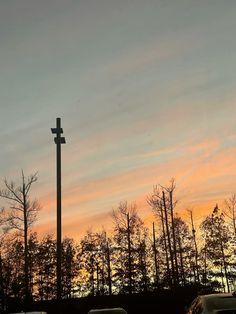 cars parked in front of a cross at sunset