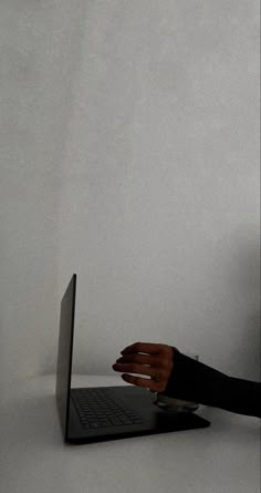 a person sitting in front of a laptop computer with their hand on the keyboard,