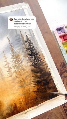 someone is painting trees with watercolors on the paper and using a paintbrush