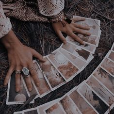 a person's hand resting on top of several pictures in the grass with their fingers touching each other