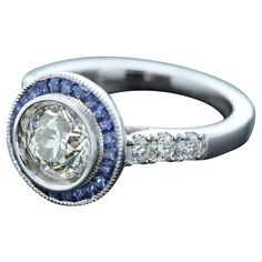 Art Deco Style Bold Ring Center is 1.25 carat Diamond surrounded with Blue Sapphire, sides have regular small white Diamonds All stones are Natural 18k White 5.70 grams Center Diamond is a Brilliant J-K color and SI2-I1 clean however has a very good sparkle (8.0 mm) set in a cup setting Small Diamonds 0.37 carat Blue Sapphire 0.63 carat Finger size 7 overall surface area diameter size - 12mm Art Deco Sapphire Ring, Bold Rings, Blue Sapphire Ring, Estilo Art Deco, Art Deco Diamond, Blue Sapphire Rings, Ring Style, Surface Area, Art Deco Style