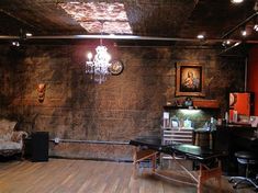 a room with wood flooring and stone walls has a chandelier hanging from the ceiling