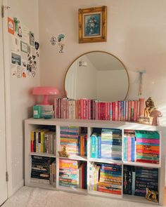 a bookshelf filled with lots of books next to a mirror