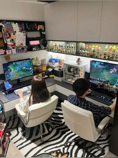 two people sitting in chairs playing video games on their computer screens and laptops at the same desk