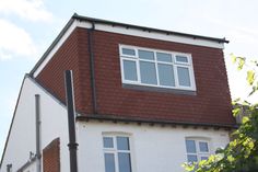 a tall white building with a red roof and two windows on the top of it