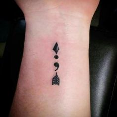 a small arrow tattoo on the wrist with an arrow and two arrows in it,