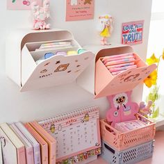 there is a desk with lots of books and toys on it in the room that has pink walls