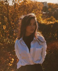 a woman in a white shirt and black skirt posing for the camera with her hands on her hips