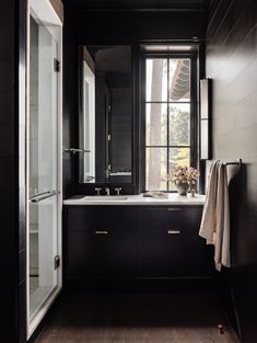 a black and white bathroom with wood floors, large windows, and wooden flooring