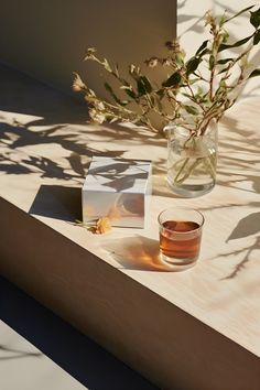 A glass of tea bathed in the glow of low sunlight on a table.