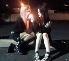 two young women sitting on the ground with one holding a lit candle in her hand