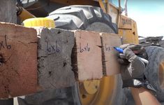 a person is holding a piece of wood in front of a tractor