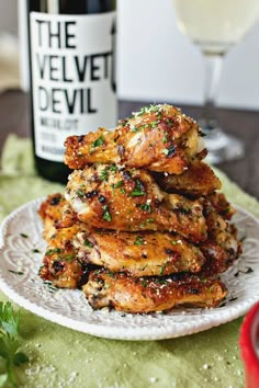 some chicken wings are stacked on a plate next to a bottle of wine