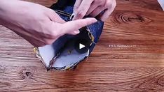 a person opening up a pair of jeans on top of a wooden floor next to a laptop