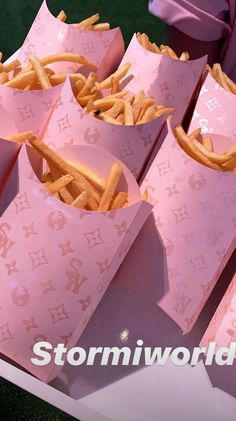 pink paper bags filled with french fries on top of a table