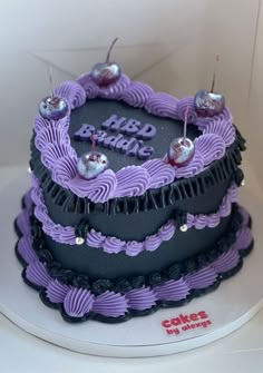 a three tiered cake with purple frosting and black icing on it's sides