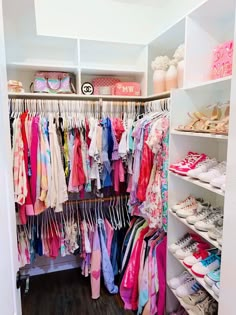 a closet filled with lots of colorful clothes and shoes on shelve shelves next to each other