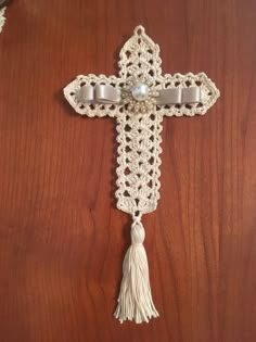 a crocheted cross with tassels and pearls hanging on a wooden door