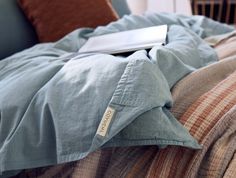 an open laptop computer sitting on top of a bed covered in blue sheets and blankets