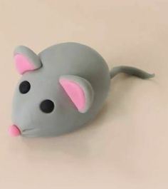 a gray and pink toy mouse laying on top of a table