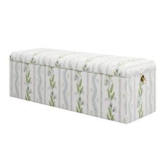 an upholstered storage box with green and white designs on the lid, in front of a white background