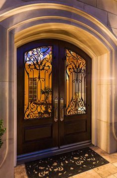 the front door is decorated with wrought iron designs and glass panels, along with a potted plant