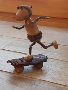 a statue of a dog riding a skateboard on top of a wooden floor next to a wall