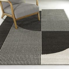 a chair sitting on top of a rug next to a gray and black chair in a room