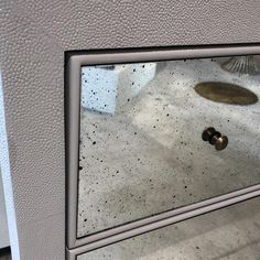 a close up of a mirror on the side of a wall with a door handle