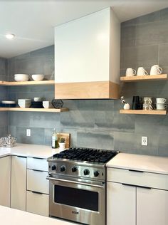 a stove top oven sitting inside of a kitchen next to white cabinets and counter tops