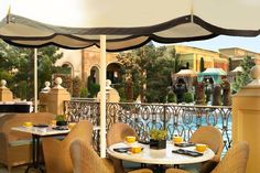 an outdoor dining area with tables, chairs and umbrellas next to a swimming pool