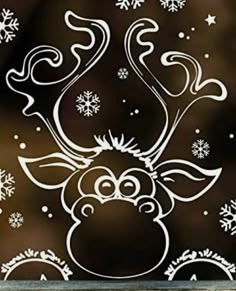 a window with snowflakes on it and a reindeer face drawn in white ink