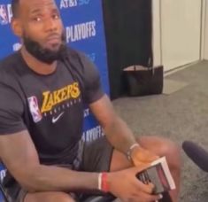 a man sitting on top of a chair next to a basketball hoop with a book in his hand