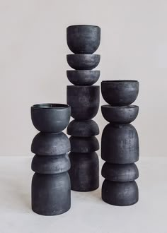 a stack of black vases sitting next to each other on top of a table