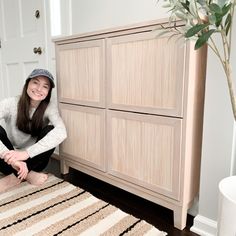 a woman sitting on the floor in front of a dresser with drawers and rugs