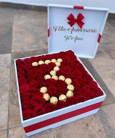 red roses in a white box with gold foiled chocolates arranged in the shape of a s