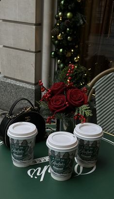 three cups of coffee sitting on top of a table next to a purse and flowers